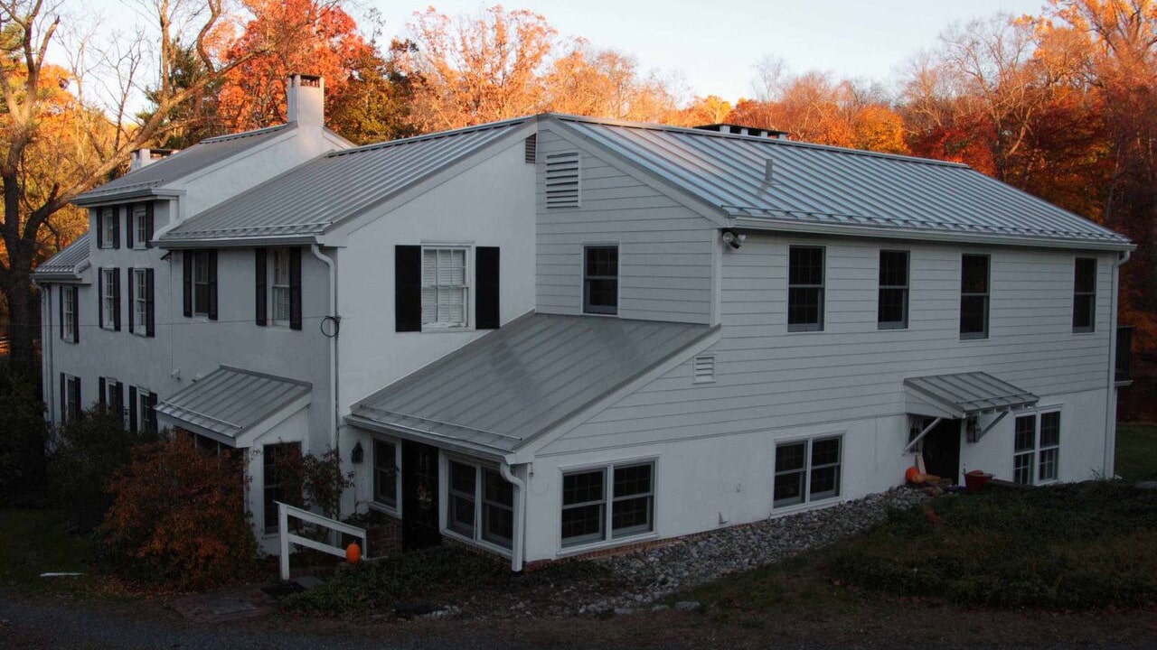 white 1820 Chester County Farmhouse with Galvalume standing seamed roofing, James Hardie siding and chimney repair